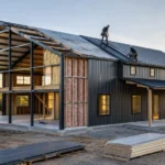 Barndominium construction with dark grey metal roof half-way built