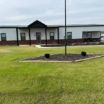 Completed white and black Tennessee barndominium with a metal roof and landscaped yard